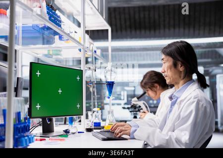 Chroma key computer application used by senior laboratory technician for DNA data analysis. Asian research facility worker using bioinformatics genomics software on green screen PC Stock Photo