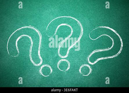Three question marks drawn on green chalkboard Stock Photo