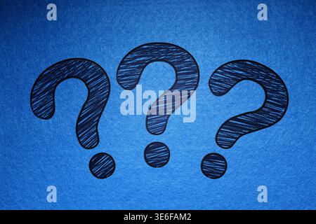 Three question marks drawn on blue background Stock Photo