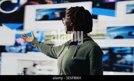 Happy person delighted by clips, enjoying technology bridging people worldwide. Jolly woman with arms wide open using digital interface to look at videos, enjoying digital age lifestyle, camera B Stock Photo