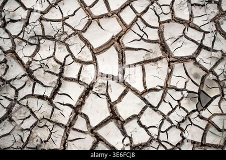 Close-up of cracked dry earth forming an abstract mud pattern. Natural arid ground texture background illustrating drought, heat, water shortage, and Stock Photo