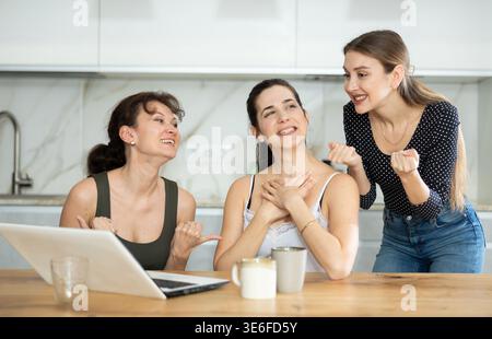 Women are sitting at computer and are immensely happy, exclaim joyfully ...