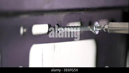 Screw being fastened into a wall using a drill bit during home improvement project in a room Stock Photo