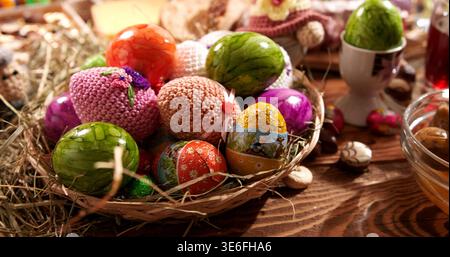 Colorful eggs in a basket on a wooden table during a festive spring celebration in a cozy indoor setting Stock Photo