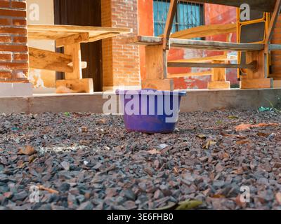The blue bucket is in the backyard, near the house. The area is surrounded by wooden benches and brick walls. The scene evokes the concept of a blue b Stock Photo