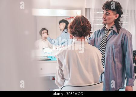 Two makeup artists are working together, applying makeup on a model in a professional beauty salon, showcasing teamwork and creativity in the beauty i Stock Photo