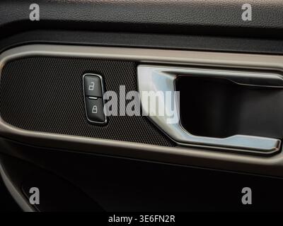Close up of modern car interior door handle with lock and unlock buttons showing textured panel and metallic trim detail Stock Photo