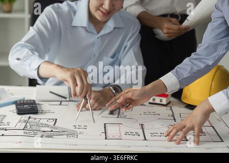 Two architects engage in a collaborative session, analyzing blueprints and discussing placement while sharing ideas at a well-organized workspace Stock Photo