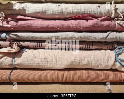 Soft, pastel colored muslin baby blankets folded and stacked, creating a warm and inviting atmosphere, perfect for a nursery or baby shower Stock Photo
