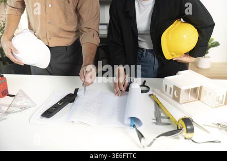 Two architects discussing blueprints and building models in a modern office, showcasing teamwork and design Stock Photo
