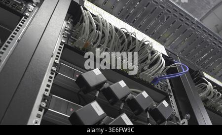 Storage servers are located in the server room of the data center. Back of the server installed in the server room. Many cables are connected to a pow Stock Photo