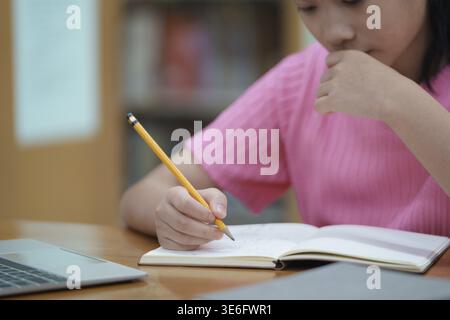 Elementary school girl studying or doing home work, close up. close up shot of girl hands writing or making notes on study desk at home Stock Photo