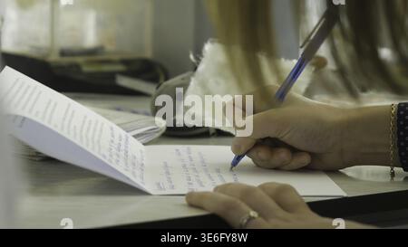 Closeup of a female hand writing on an blank notebook with a pen. Close-up of a female hand writing on an blank notebook with a pen 4K Stock Photo