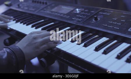 Woman plays by hands on white digital piano, close-up shooting with defocus. Stock. Girl is playing by fingers on keyboard or synthesizer Stock Photo