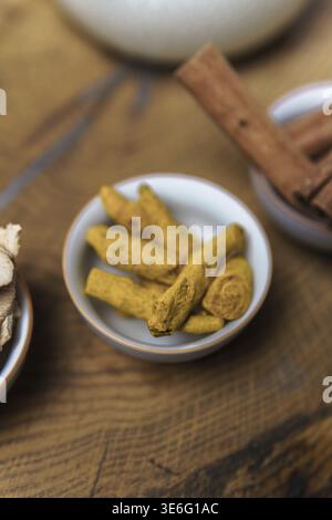 Beautifully displayed organic turmeric roots along with fresh cinnamon sticks on a rustic natural wood surface Stock Photo