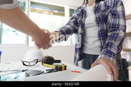 Two engineers sealing a deal with a handshake, symbolizing collaboration and partnership in construction projects Stock Photo