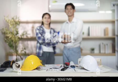 Two engineers pose in a contemporary office, showcasing teamwork and professionalism in construction planning Stock Photo