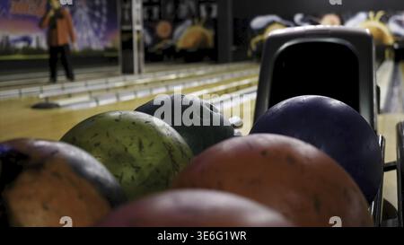 Close-up of young man taking bowling balls from the rack. Media. Competitive cheerful friends playing bowling together in the club Stock Photo