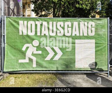 Vienna, Austria - 12. July 2025: Green emergency exit sign with running man and arrows pointing to escape route, indicating safe passage in Vienna Stock Photo