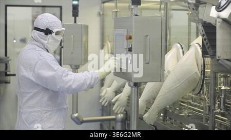 Worker at pharmaceutical factory operating control panel of the pharmaceutical machine. Pharmaceutical Factory Workers. Pharmaceutical Manufacturing Stock Photo