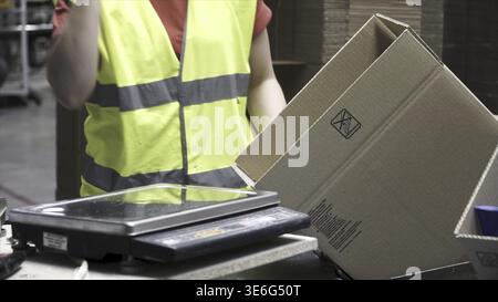 Close-up view of the hands of a manufacturing worker putting packed products in cardboard boxes, before export or shipping during manual work in a cos Stock Photo