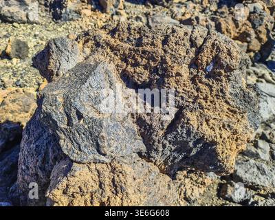 Rough and porous volcanic rock surface displaying diverse textures and colors. A natural geological formation from ancient lava flows Stock Photo