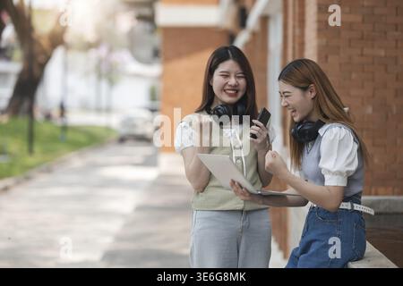 Beautiful young Asian woman college student with friends at outdoors. College student working on the college campus Stock Photo