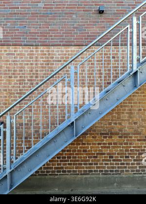 Close up view on metallic stairs in front of a brick wall Stock Photo