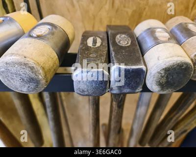 Close up view of various old hammers and mallets hanging on a workshop rack, showcasing traditional craftsmanship Stock Photo
