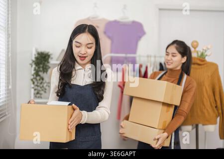Two diverse female e-commerce employees handling packages and preparing for shipment in a retail store environment Stock Photo