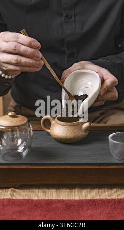 A close-up of an intricate tea ceremony where delicate tea leaves are carefully poured into a teapot Stock Photo