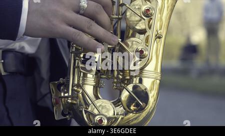 Young man with saxophone outside near the old painted wall. Young expressive musician playing the saxophone. Art and music. Jazz music Stock Photo
