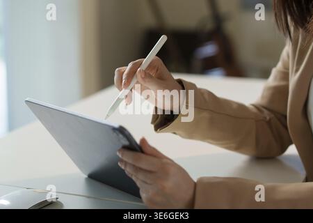 Businesswoman using stylus interacting with digital tablet displaying data charts and graphs, close up of hand and device, focusing on technology usag Stock Photo
