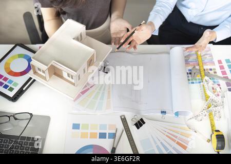 Designers planning a project with color samples and a model, discussing ideas and strategies in a collaborative workspace Stock Photo
