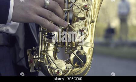 Young man with saxophone outside near the old painted wall. Young expressive musician playing the saxophone. Art and music. Jazz music Stock Photo