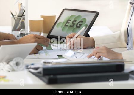 Business team collaborates on ESG strategies, analyzing data and discussing sustainability initiatives in a modern office Stock Photo
