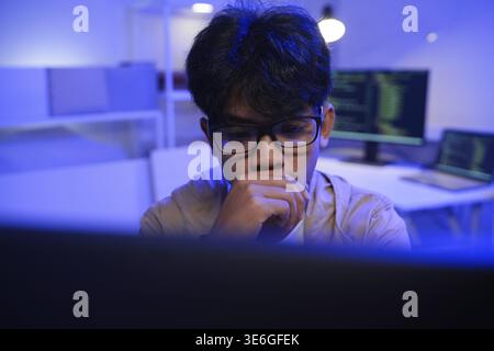 Male Software Engineer Writing Code on Desktop Computer with Multiple Screens Setup. Data center programmer managing large datasets used in AI trainin Stock Photo