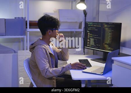 Male Software Engineer Writing Code on Desktop Computer with Multiple Screens Setup. Data center programmer managing large datasets used in AI trainin Stock Photo