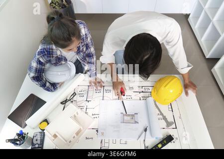 Two engineers discussing building plans and designs in a modern workspace, showcasing teamwork and project planning Stock Photo