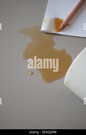 Coffee spills on the table near a notepad and pencil Stock Photo