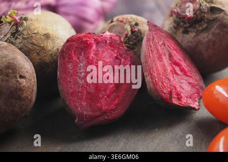 Beets cut in half next to whole beets on wooden table Stock Photo