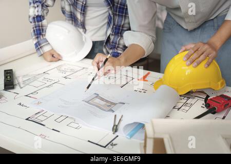 Engineers working together on construction plans, highlighting teamwork and attention to detail in a professional environment Stock Photo