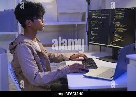 Male Software Engineer Writing Code on Desktop Computer with Multiple Screens Setup. Data center programmer managing large datasets used in AI trainin Stock Photo
