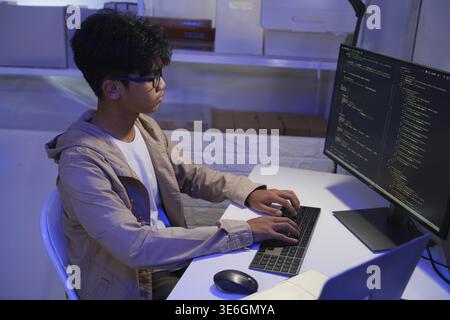Male Software Engineer Writing Code on Desktop Computer with Multiple Screens Setup. Data center programmer managing large datasets used in AI trainin Stock Photo