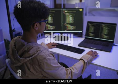 Male Software Engineer Writing Code on Desktop Computer with Multiple Screens Setup. Data center programmer managing large datasets used in AI trainin Stock Photo