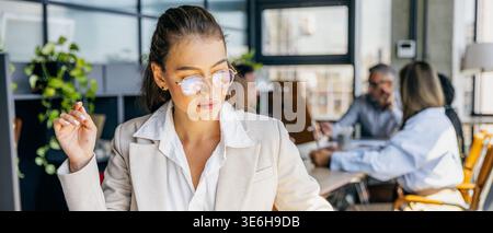Engaged woman collaborates with team in welllit environment Stock Photo