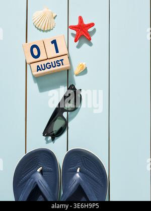 Summer composition made of beach accessories and wooden block calendar showing August 1st, evoking concept of summer vacation Stock Photo