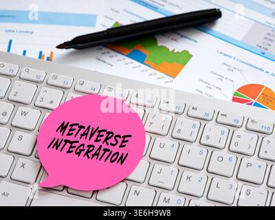 Pink speech bubble with metaverse integration handwritten, resting on a computer keyboard amid charts and graphs, symbolizing virtual and real-world b Stock Photo