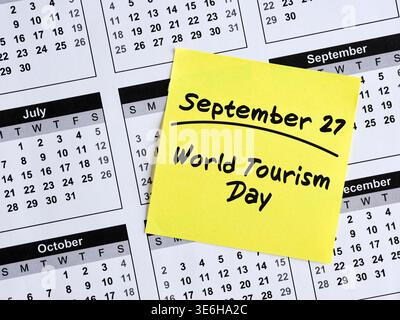 Yellow sticky note with handwritten text September 27, world tourism day resting on calendar page Stock Photo