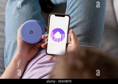 A man holds a smartphone with the Yandex Alice AI app and adjusts the Alice speaker. Saint Petersburg, Russia - 7 Apr 2026 Stock Photo